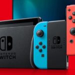 Official Nintendo Switch console with red and blue Joy-Con controllers docked for TV mode on a red and black background.